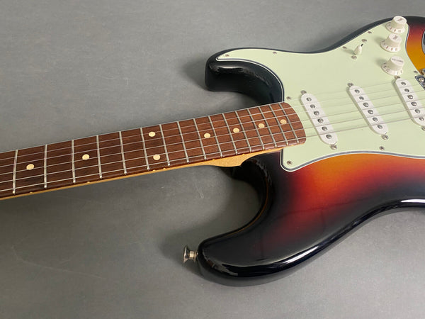 Sunburst electric guitar body with white pickguard and rosewood fretboard on gray background