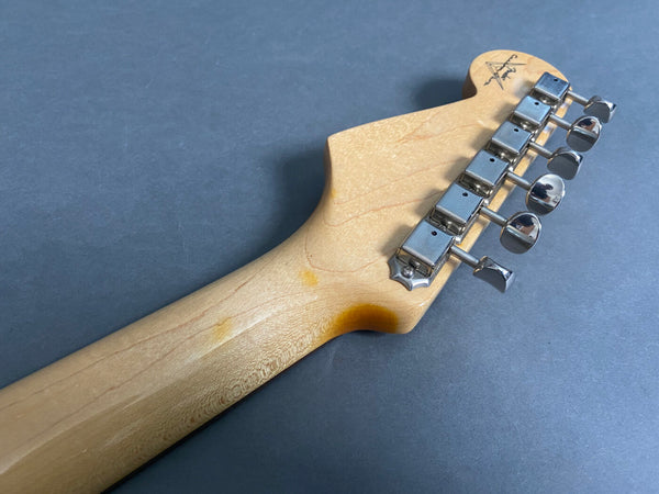 Close-up of guitar neck headstock showing tuners and wood grain on maple neck with vintage-style tuning pegs