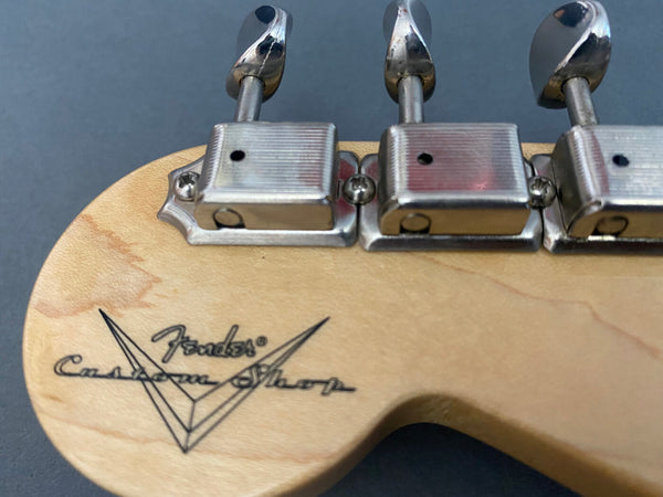 Close-up of Fender Custom Shop guitar headstock with vintage-style tuning machines and logo on natural wood finish