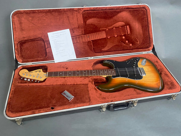 Fender Stratocaster electric guitar with sunburst finish in vintage brown plush lined hardshell case including tremolo arm and inspection checklist from Coffee House Guitars