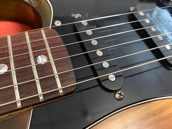 Close-up of acoustic guitar fretboard and black electric guitar pickups with strings over a wooden guitar body edge