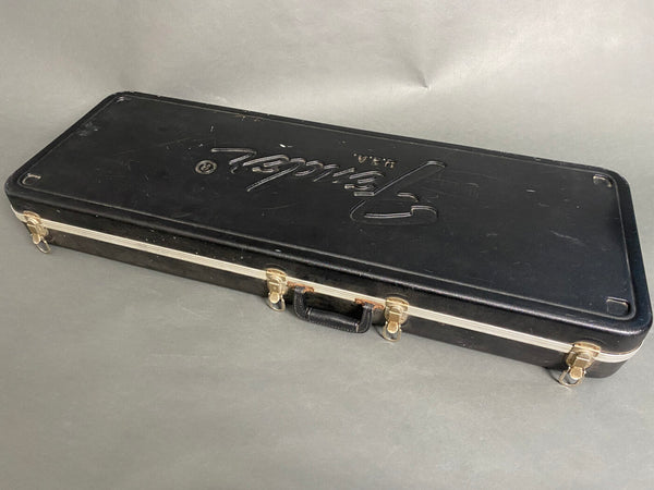 Black vintage Fender USA hard guitar case with metal latches and handle on gray background