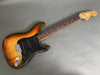Fender Stratocaster electric guitar with sunburst finish, black pickguard, and rosewood fingerboard, laid on gray background