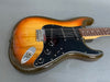 Sunburst electric guitar with black pickguard, three single-coil pickups, and volume and tone control knobs on gray background.