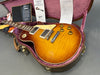Gibson Les Paul electric guitar in sunburst finish with gold hardware and cream pickguard in open brown hardshell case with plush pink interior and Gibson Gold Warranty certificate visible
