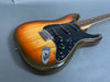 Sunburst electric guitar with black pickguard and three single-coil pickups on gray background