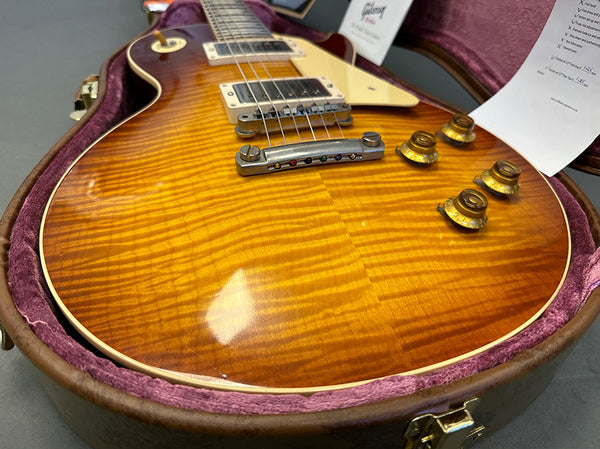 Close-up of sunburst flamed maple top electric guitar with gold control knobs and cream pickguard in a purple plush-lined guitar case at Coffee House Guitars.
