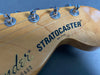 Close-up of Fender Stratocaster guitar headstock with tuning pegs and "Made in USA" marking on natural wood finish