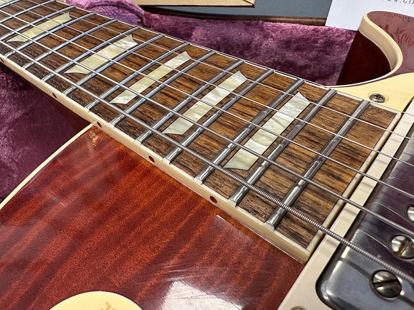 Close-up of electric guitar fretboard with mother-of-pearl inlays and steel strings on a richly grained wood body at Coffee House Guitars