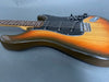 Sunburst electric guitar body with black pickguard and three single-coil pickups on gray background