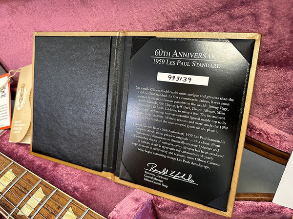60th Anniversary 1959 Les Paul Standard certificate of authenticity in a guitar case with pink plush lining and a portion of the guitar neck visible