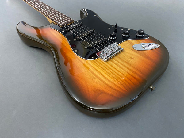 Electric guitar with sunburst finish, black pickguard, and three control knobs on gray background