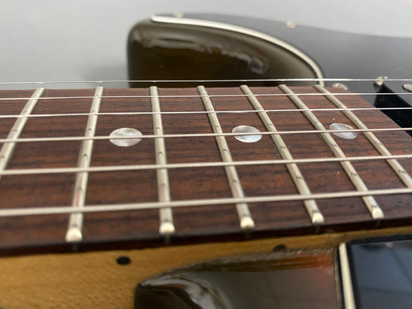 Close-up of electric guitar rosewood fretboard with metal frets and string detail against black body background