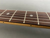 Close-up of guitar fretboard with metal frets and dot inlays on rosewood fingerboard and maple neck side marker dot
