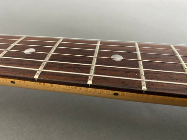 Close-up of guitar fretboard with metal frets and dot inlays on rosewood fingerboard and maple neck side marker dot