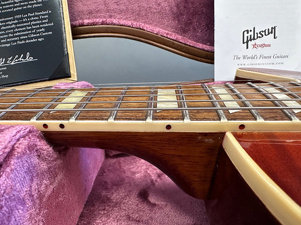 Close-up of Gibson Les Paul guitar neck and fretboard with cream binding and trapezoid inlays inside pink plush guitar case