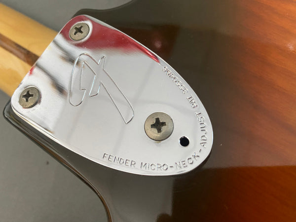 Close-up of Fender Micro-Neck adjustable chrome neck plate on sunburst electric guitar body with three screws