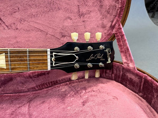 Close-up of Gibson Les Paul model guitar headstock with tuning pegs inside pink velvet-lined guitar case