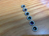 Guitar bridge pin replacement springs with colored coils on wood surface for acoustic guitar maintenance