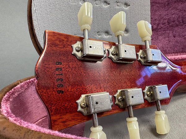 Close-up of vintage guitar headstock with serial number 993139 and vintage tuning pegs inside a plush guitar case