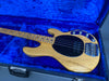 Natural wood finish electric bass guitar with black pickguard and chrome hardware lying in blue plush-lined guitar case