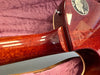 Close-up of Gibson guitar neck joint showing mahogany wood grain and 125th Anniversary 1894-2019 commemorative plaque on guitar body resting in pink plush case lining.