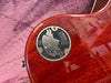 Close-up of Gibson Custom 60th Anniversary 1959 Les Paul guitar commemorative metal badge on polished mahogany back body with pink fabric background