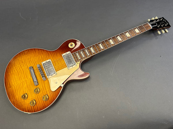 Electric guitar with sunburst finish, dual humbucker pickups, cream pickguard, rosewood fretboard with block inlays, and vintage-style tuning pegs on dark background