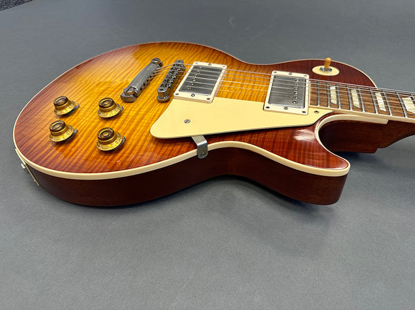 Electric guitar with sunburst finish, dual humbucker pickups, four control knobs, and cream pickguard on gray background