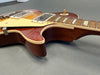 Close-up of sunburst finish electric guitar body with dual humbucker pickups and cream pickguard on gray surface