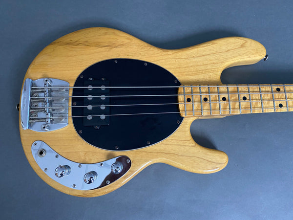 Natural finish electric bass guitar with black pickguard, chrome bridge and control knobs, and maple neck with dot inlays on the fretboard