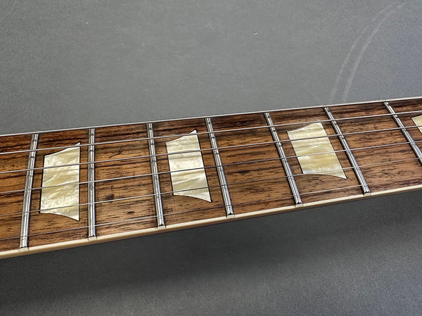 Close-up of rosewood guitar fretboard with pearloid trapezoid inlays and metal frets on Coffee House Guitars electric guitar.