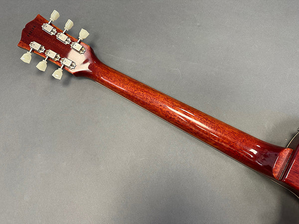 Back of guitar neck showing mahogany wood and tuning pegs on gray background
