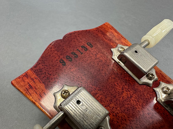 Close-up of vintage guitar headstock back showing serial number 993139 and Grover tuning machines with cream tuning pegs on reddish-brown wood finish