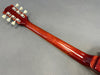 Back of guitar neck with six tuning pegs and glossy reddish wood finish on gray background