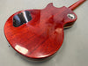 Back of glossy cherry red electric guitar body showing wood grain and black plastic control cavity cover.