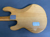 Back side of natural wood electric guitar body with metal neck plate and back control cover on gray surface