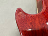 Close-up of red stained wood grain on electric guitar body corner with glossy finish at Coffee House Guitars