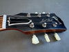 Close-up of Gibson Les Paul Model guitar headstock with tuning pegs and strings against gray background