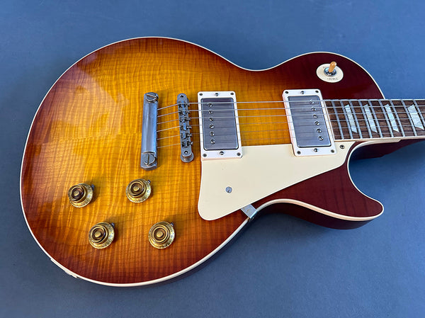 Sunburst finish electric guitar with humbucker pickups and cream pickguard on blue background