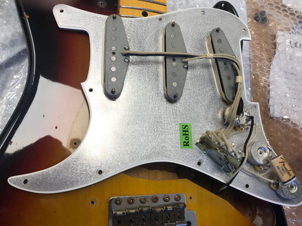 Fender Stratocaster vintage three single-coil pickups wiring assembly with tone and volume potentiometers on a silver pickguard above a sunburst guitar body