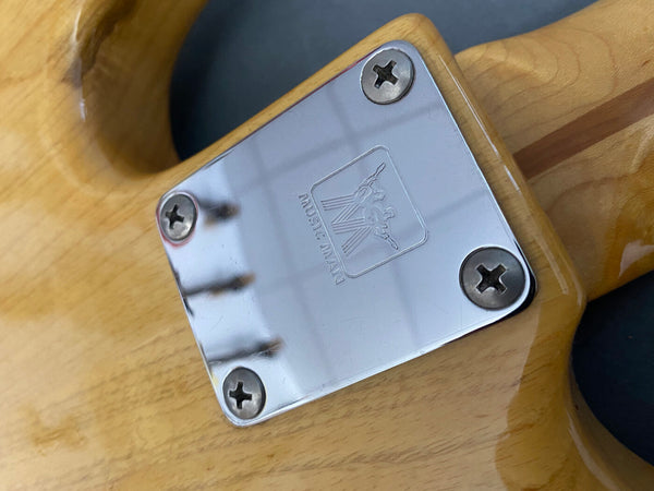 Close-up of Music Man guitar neck plate with four screws on natural wood finish guitar body