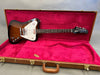 Gibson Thunderbird electric guitar with sunburst finish in open brown hard case with red plush interior, featuring maple and rosewood neck and custom pickguard.