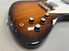 Close-up of sunburst electric guitar body showing tone and volume control knobs and input jack on gray background