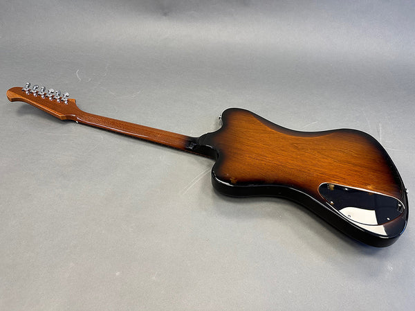Rear view of vintage sunburst electric guitar with maple neck and chrome tuning pegs on gray background