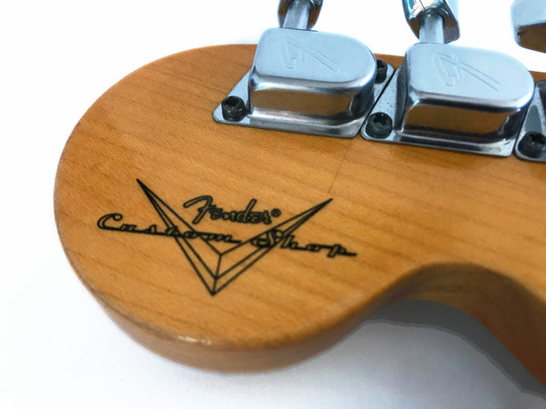 Close-up of Fender Custom Shop guitar headstock with tuning pegs and logo on natural wood finish