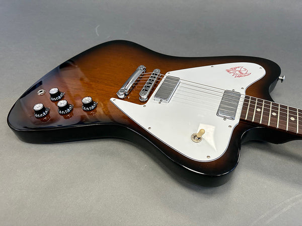 Sunburst electric guitar with white pickguard and chrome hardware on gray background