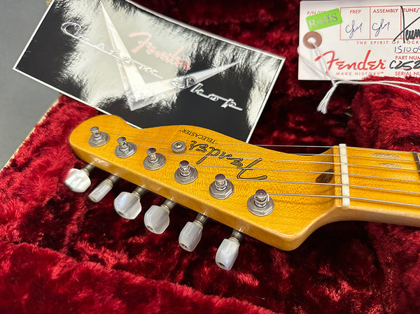 Close-up of Fender Telecaster guitar headstock with tuning pegs, certificate and Fender custom shop tag on red velvet background