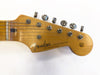Close-up of Fender Stratocaster guitar headstock with natural wood finish and six tuning pegs on a white background