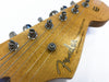 Close-up of Fender Stratocaster guitar headstock with vintage tuners and strings on natural wood finish